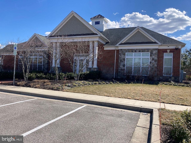 view of front of house with a front yard, uncovered parking, and brick siding