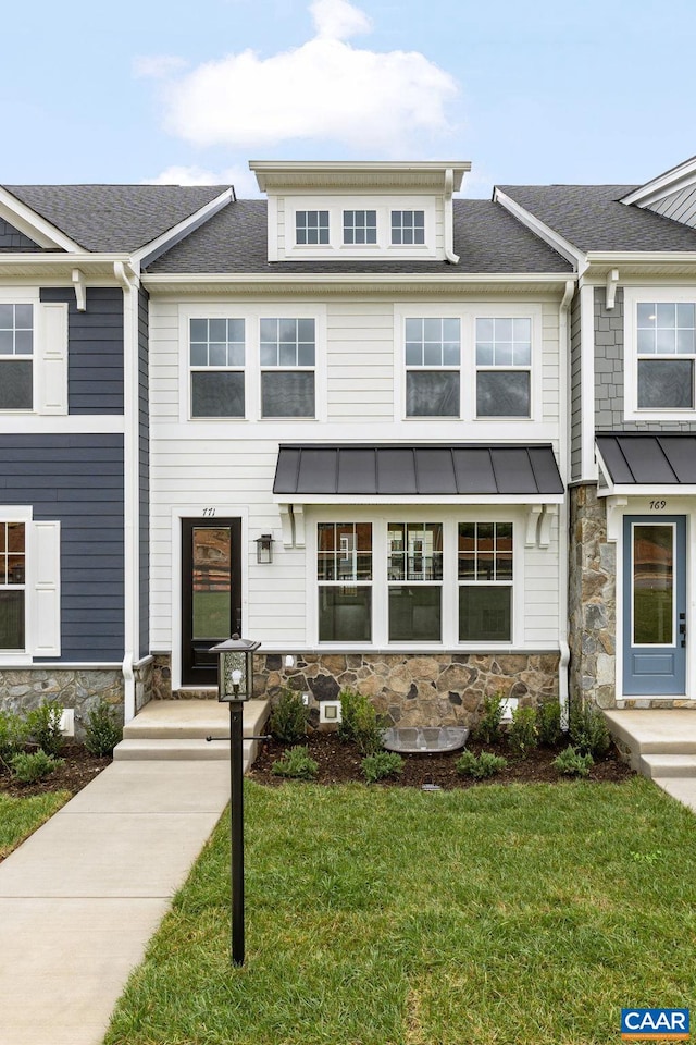 view of property with a shingled roof, a front yard, a standing seam roof, metal roof, and stone siding