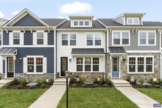 multi unit property featuring stone siding, a front lawn, and a standing seam roof