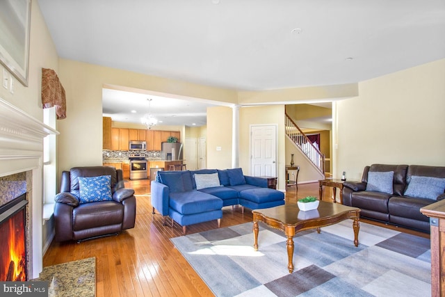 living area with light wood-type flooring, stairway, a chandelier, and a high end fireplace