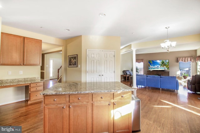 kitchen featuring light wood-type flooring, light stone countertops, open floor plan, and built in desk