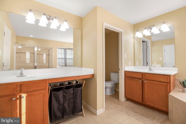 bathroom with toilet, vanity, baseboards, tile patterned floors, and a stall shower