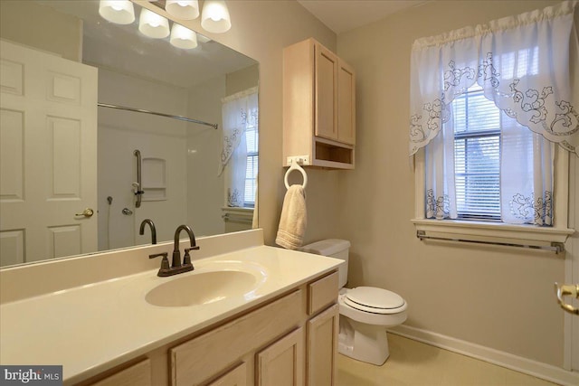 bathroom featuring a healthy amount of sunlight, toilet, vanity, and baseboards