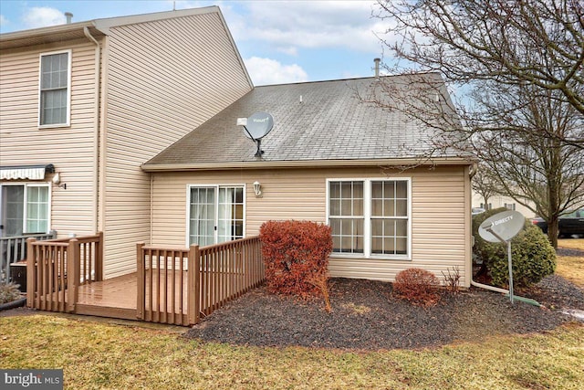 rear view of house featuring roof with shingles and a wooden deck