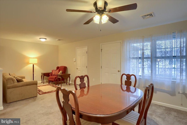 dining area featuring visible vents, light carpet, baseboards, and a ceiling fan