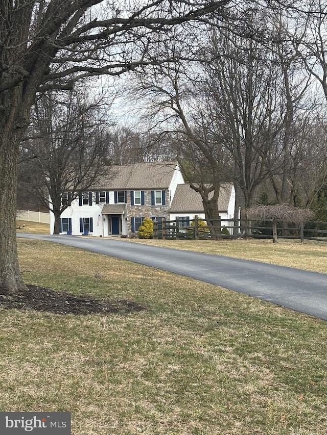 view of front of home with stone siding, a front yard, and fence