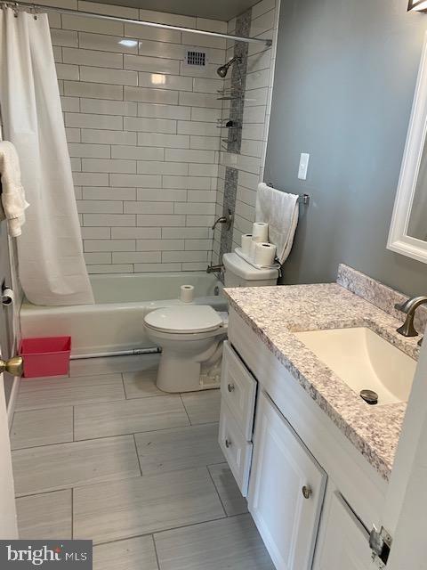 full bathroom featuring vanity, shower / bath combination with curtain, and toilet