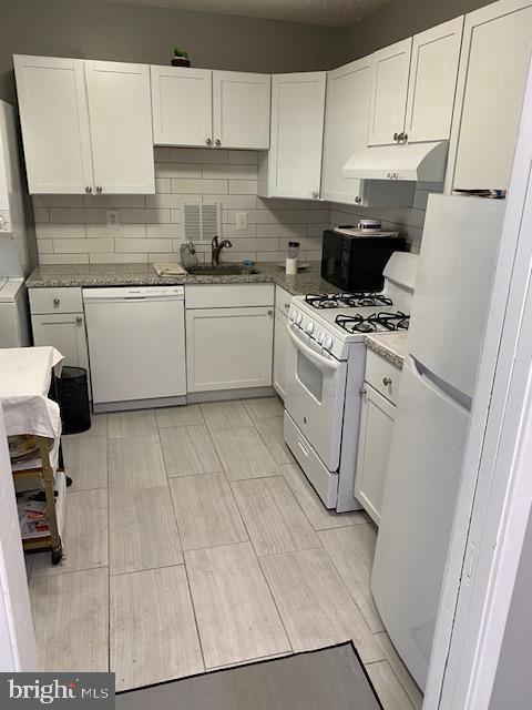 kitchen with white appliances, under cabinet range hood, and white cabinets