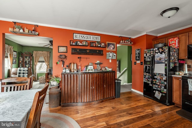 interior space with black appliances, ornamental molding, wood finished floors, and a ceiling fan