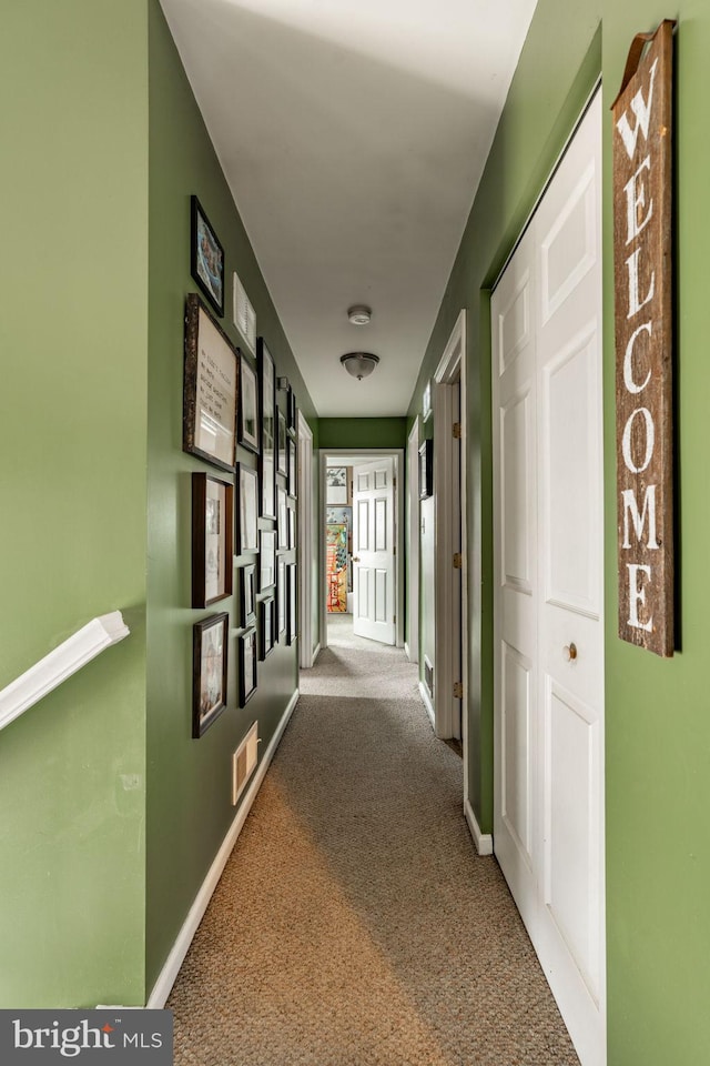 corridor featuring carpet floors, visible vents, and baseboards