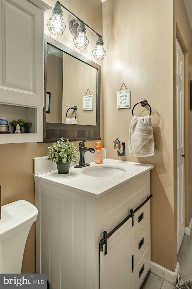 half bath featuring baseboards and vanity