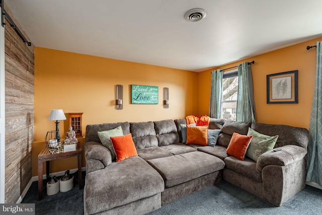 carpeted living area with a barn door and visible vents