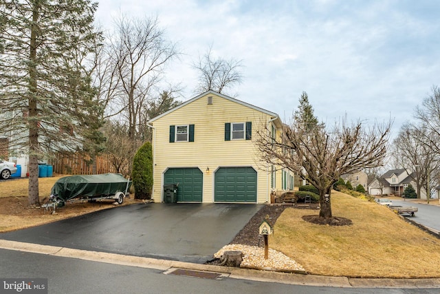 view of front of home with a garage, aphalt driveway, and a front yard