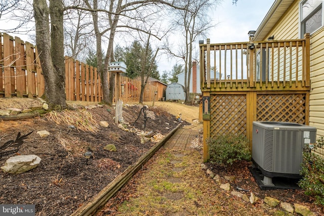 view of yard with a fenced backyard, cooling unit, a storage shed, an outdoor structure, and a wooden deck