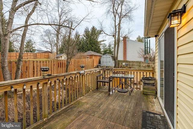 wooden deck with an outbuilding, a storage unit, and a fenced backyard