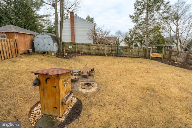 view of yard with an outdoor fire pit, an outbuilding, a fenced backyard, and a shed