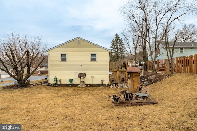 back of house with fence, a lawn, and a wooden deck