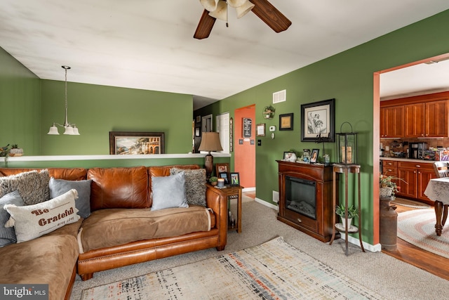 living area with a ceiling fan, visible vents, and baseboards