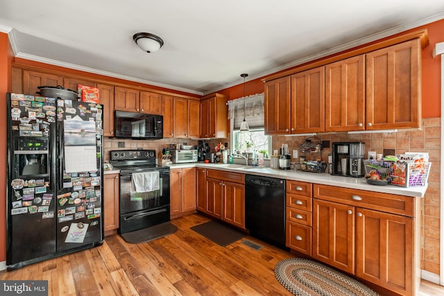 kitchen with brown cabinets, a sink, black appliances, and wood finished floors