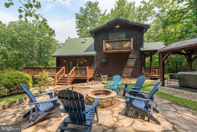 rear view of property featuring metal roof, an outdoor fire pit, a patio area, and a hot tub