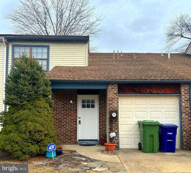 view of front of house with a garage, concrete driveway, brick siding, and roof with shingles