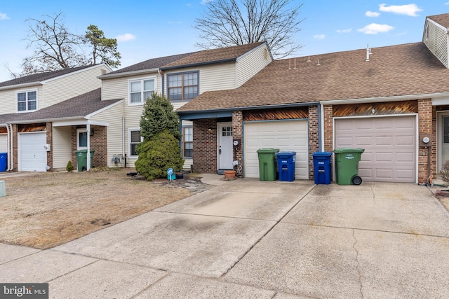 view of property with brick siding, driveway, an attached garage, and roof with shingles