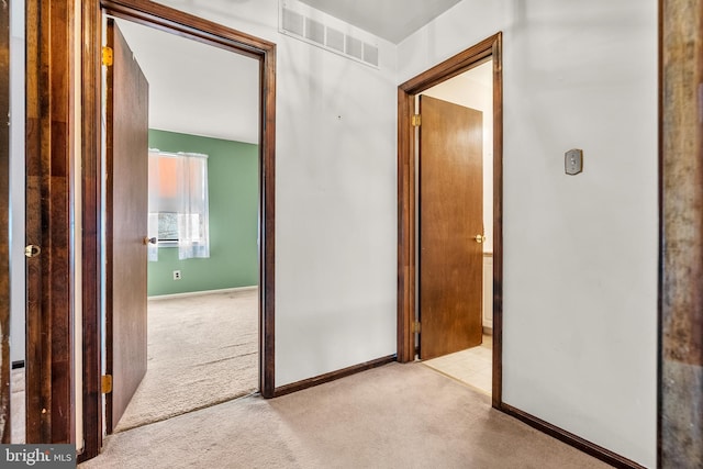 hall with light carpet, visible vents, and baseboards