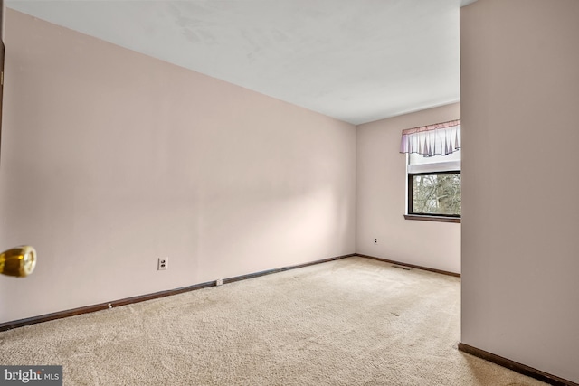 carpeted empty room featuring baseboards