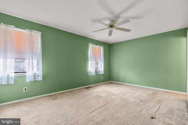 carpeted empty room with visible vents, ceiling fan, and baseboards