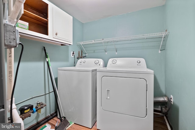 laundry room featuring cabinet space, light wood-style flooring, and washing machine and clothes dryer