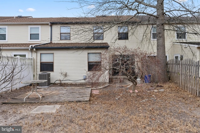 rear view of property with central AC, fence, and roof with shingles