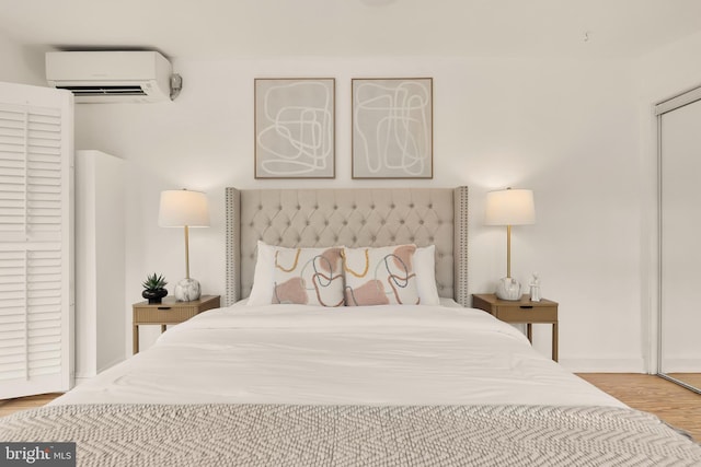 bedroom with wood finished floors and a wall mounted AC