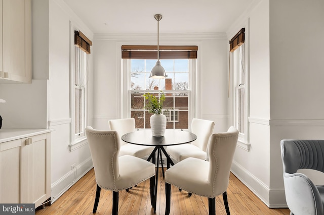 dining room featuring light wood finished floors, baseboards, and ornamental molding