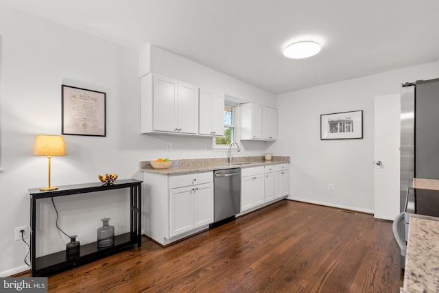 kitchen with a sink, appliances with stainless steel finishes, dark wood finished floors, and white cabinetry