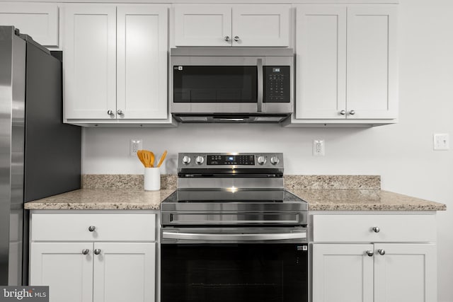 kitchen with light stone countertops, white cabinetry, and appliances with stainless steel finishes