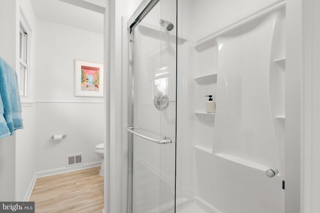 full bathroom featuring toilet, a shower stall, visible vents, and wood finished floors