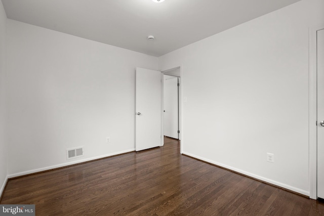 unfurnished room with baseboards, visible vents, and dark wood finished floors