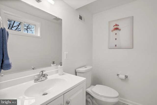 half bathroom featuring toilet, baseboards, visible vents, and vanity