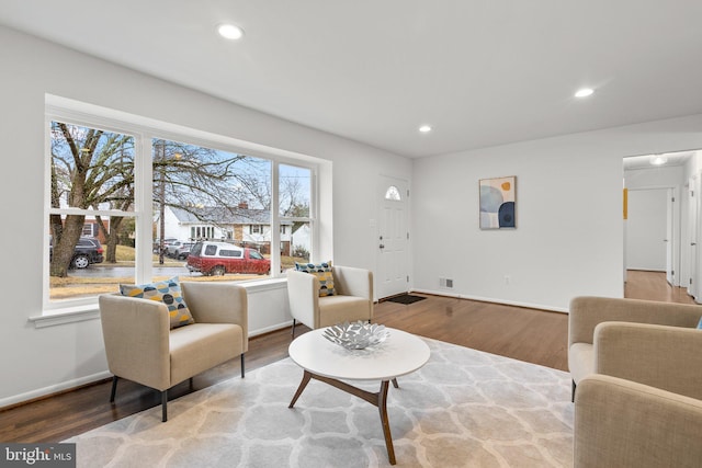 living area with baseboards, wood finished floors, and recessed lighting