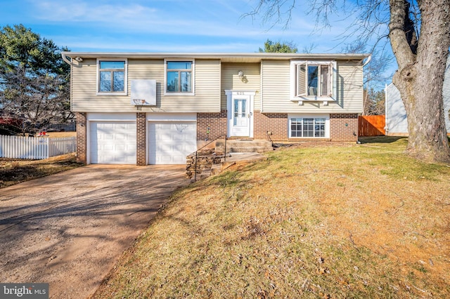 split foyer home featuring a front lawn, fence, concrete driveway, a garage, and brick siding