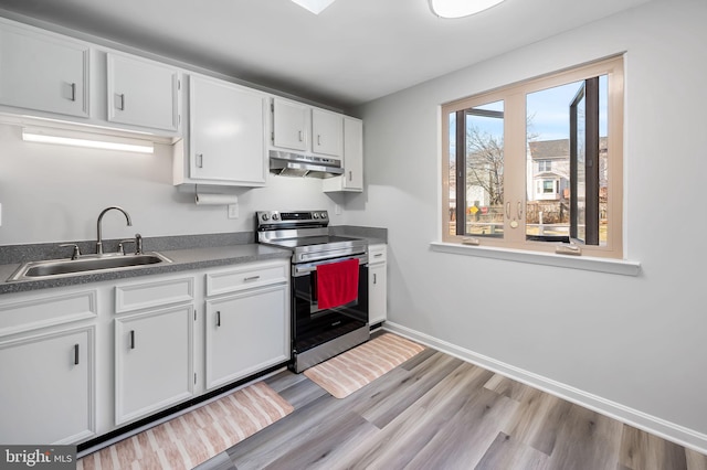 kitchen featuring light wood-type flooring, under cabinet range hood, a sink, white cabinetry, and stainless steel electric range oven