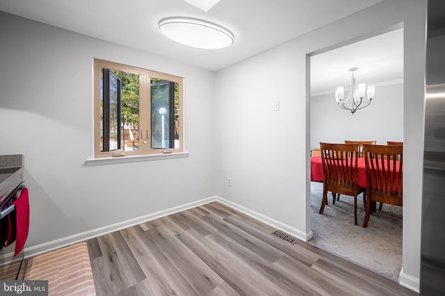 dining space featuring wood finished floors, baseboards, visible vents, and a chandelier