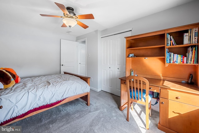 bedroom with ceiling fan, baseboards, light carpet, built in desk, and a closet