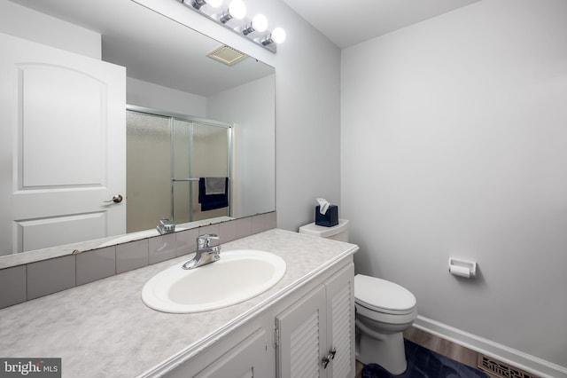 full bathroom with toilet, wood finished floors, a shower stall, baseboards, and vanity