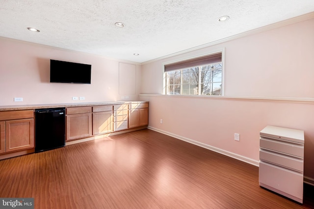 bar featuring dishwasher, wood finished floors, baseboards, and a textured ceiling