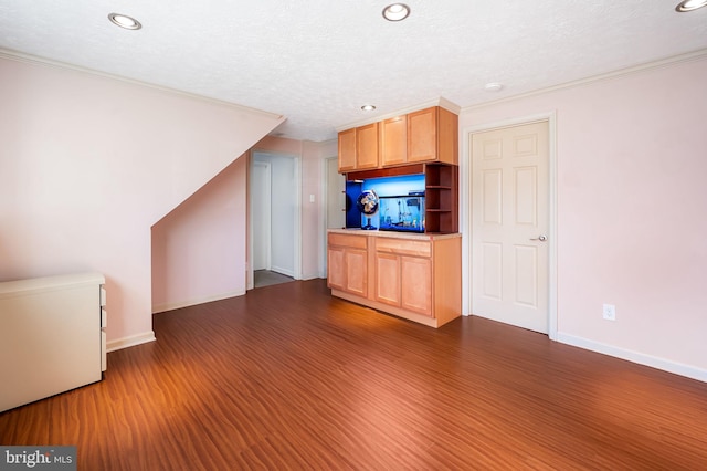 kitchen featuring baseboards, a textured ceiling, dark wood-style floors, and ornamental molding