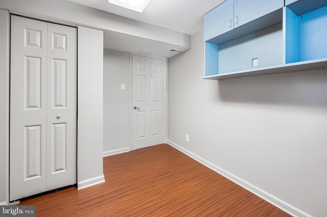 basement featuring visible vents, baseboards, and wood finished floors