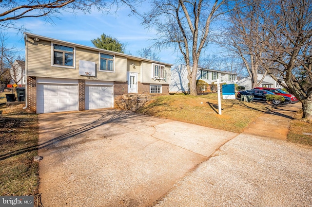 bi-level home with concrete driveway, a garage, brick siding, and a front lawn