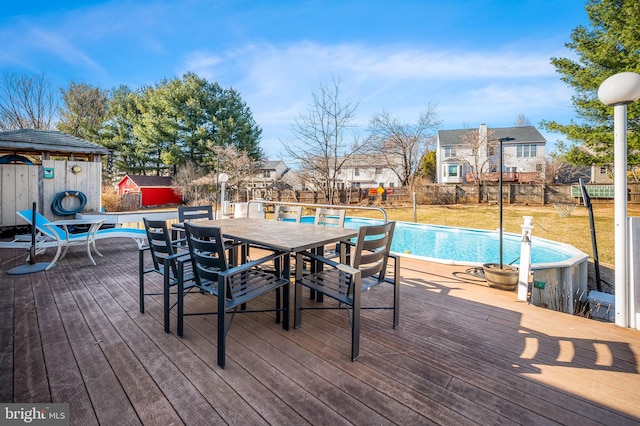 deck with a fenced backyard, outdoor dining space, a fenced in pool, and a yard