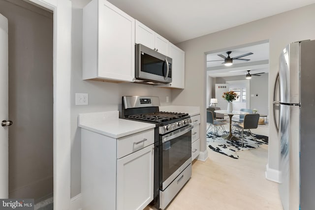 kitchen with light countertops, appliances with stainless steel finishes, light wood-style floors, white cabinetry, and baseboards